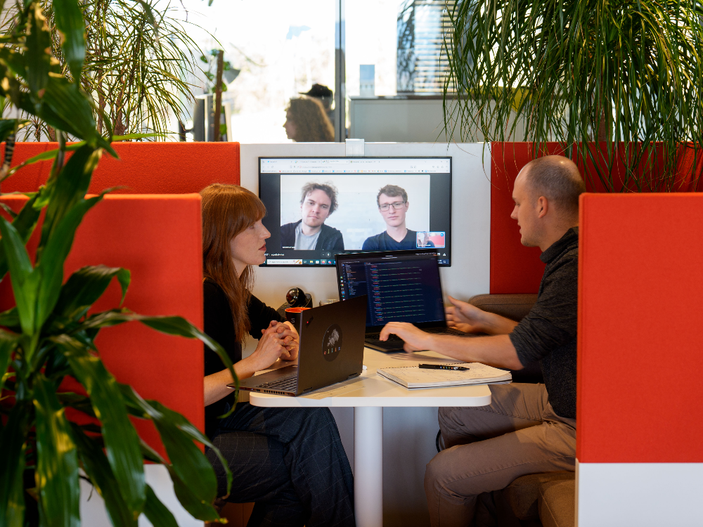 two people sitting a work booth on a video call with two people