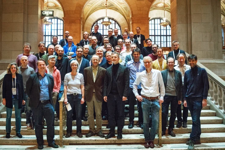 A large group of people standing on a staircase founding ELLIS in 2018 at NeurIPS