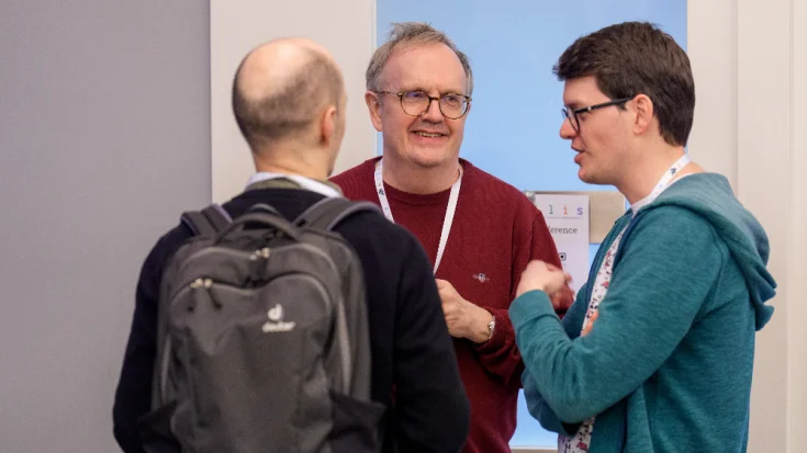 3 men speaking in a hallway