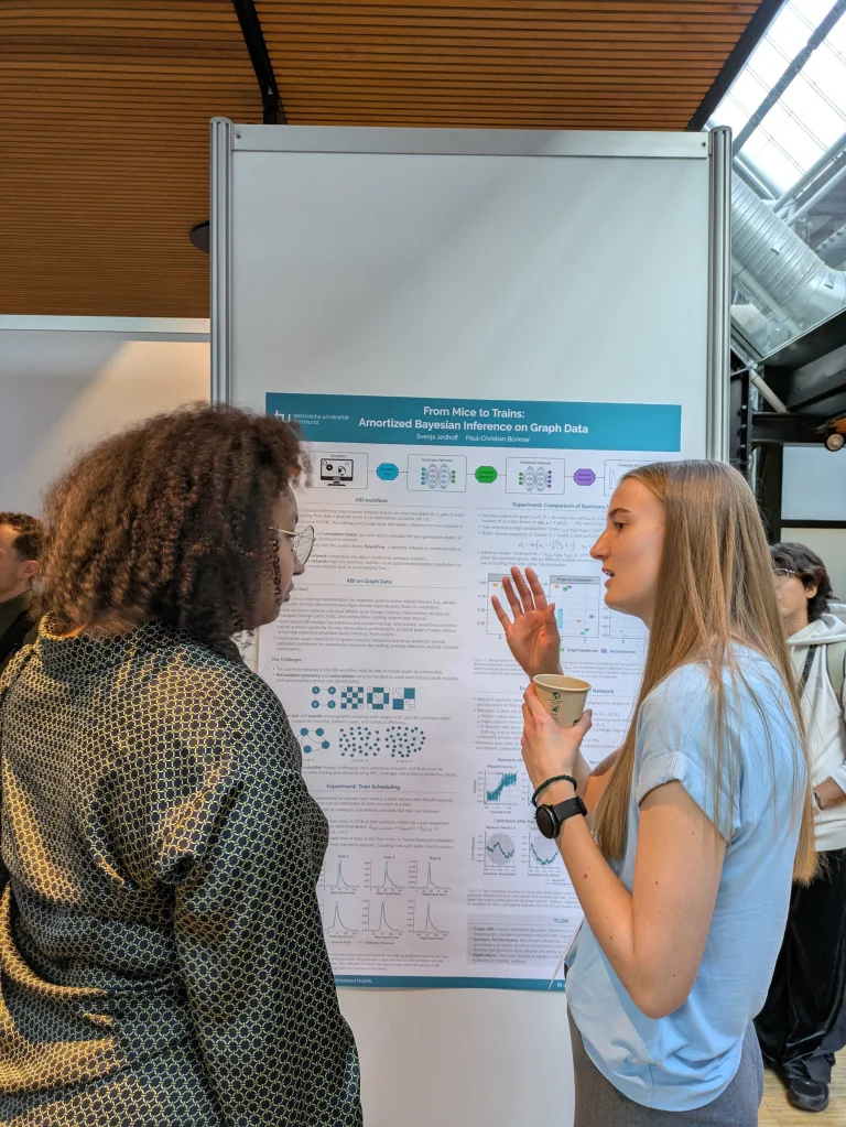 Two women talking in front of a scientific poster
