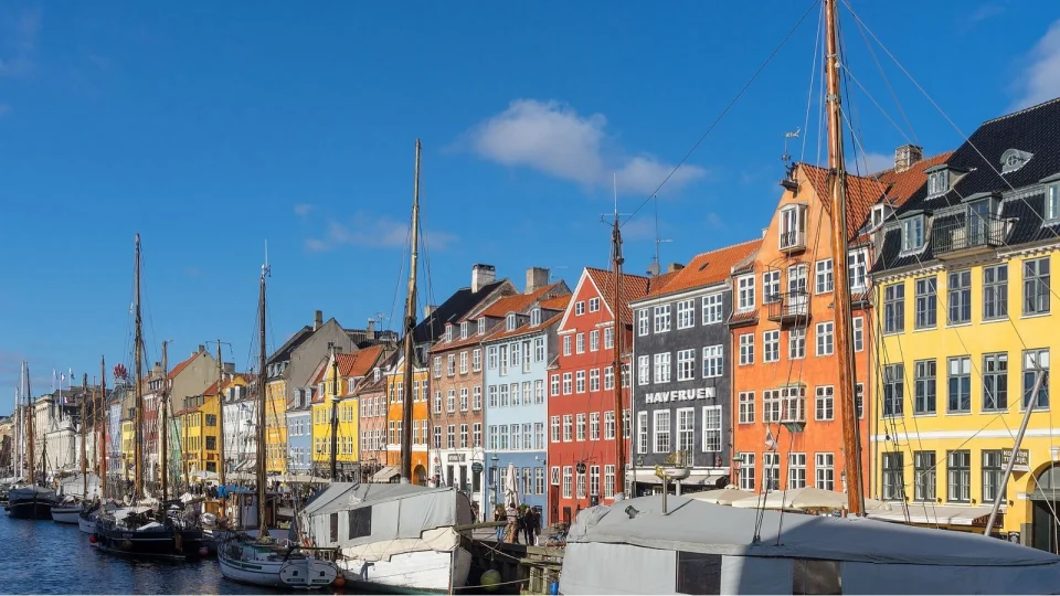 Copenhagen colorbuildings with sailboats on the water in front of them