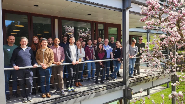 Group of scientists standing on a balcony with magnolia blossoms on the right side