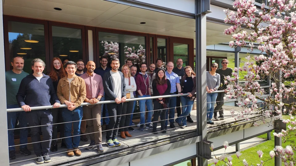 Group of scientists standing on a balcony with magnolia blossoms on the right side