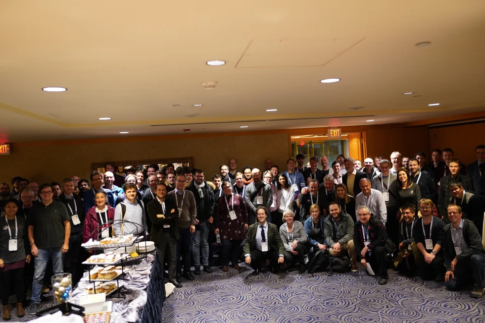 Group photo of a lot of people in a conference room smiling for a photo