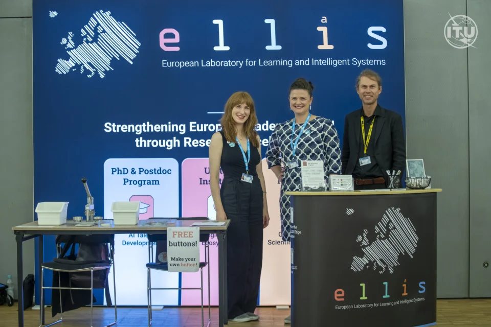 Lena Schadock, Christine Funke and Conrad Philipp standing in front of a backwall with ELLIS printed on it at the AI for Good Global Summit conference 2025