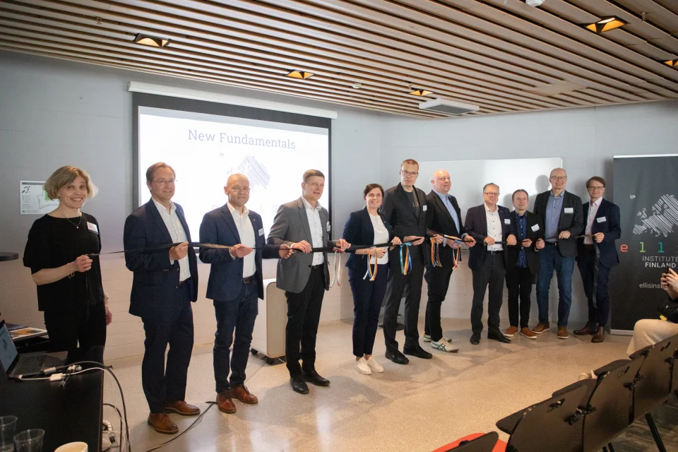 Pre-Launch of the ELLIS Institute Finland, photo of many people standing in a line holding a ribbon that will soon be cut